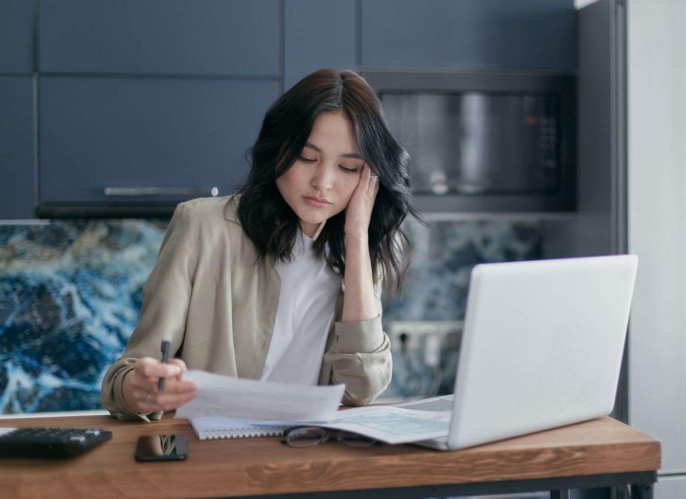 A woman reviewing a bill at her kitchen table